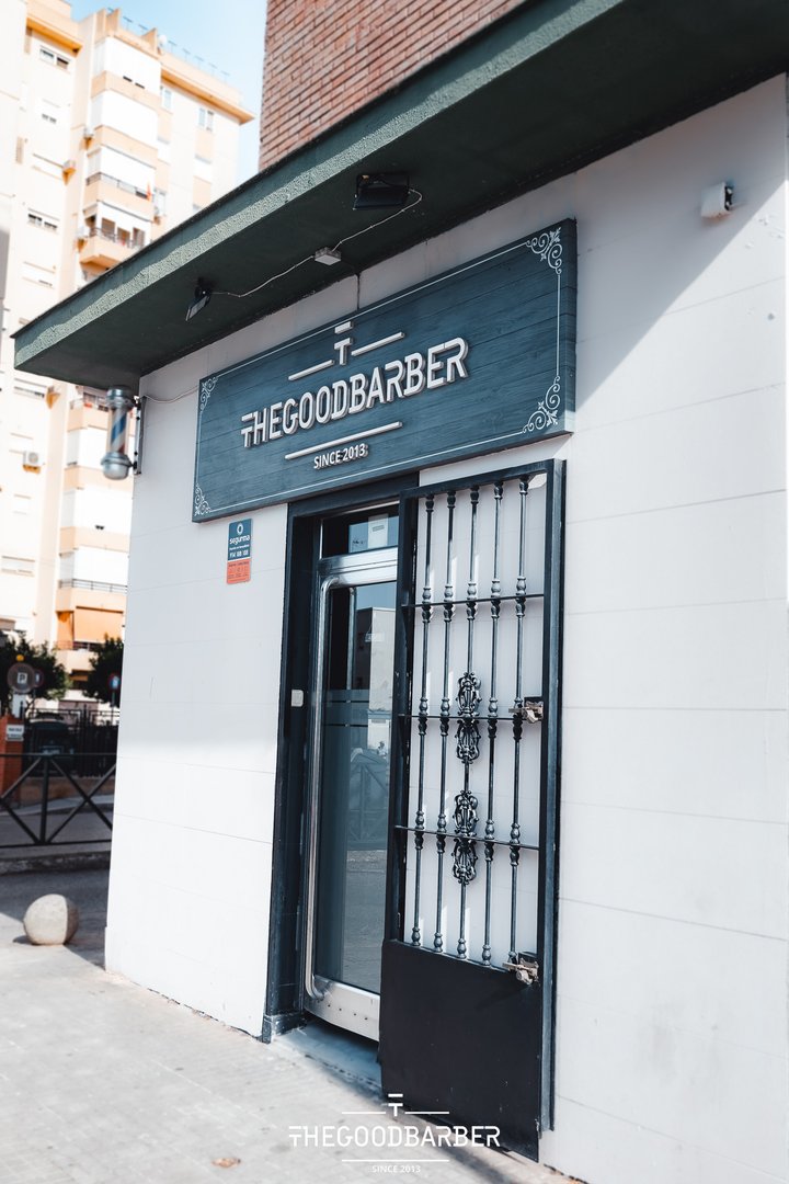 Fachada exterior de The Good Barber con rótulo y poste de barbero