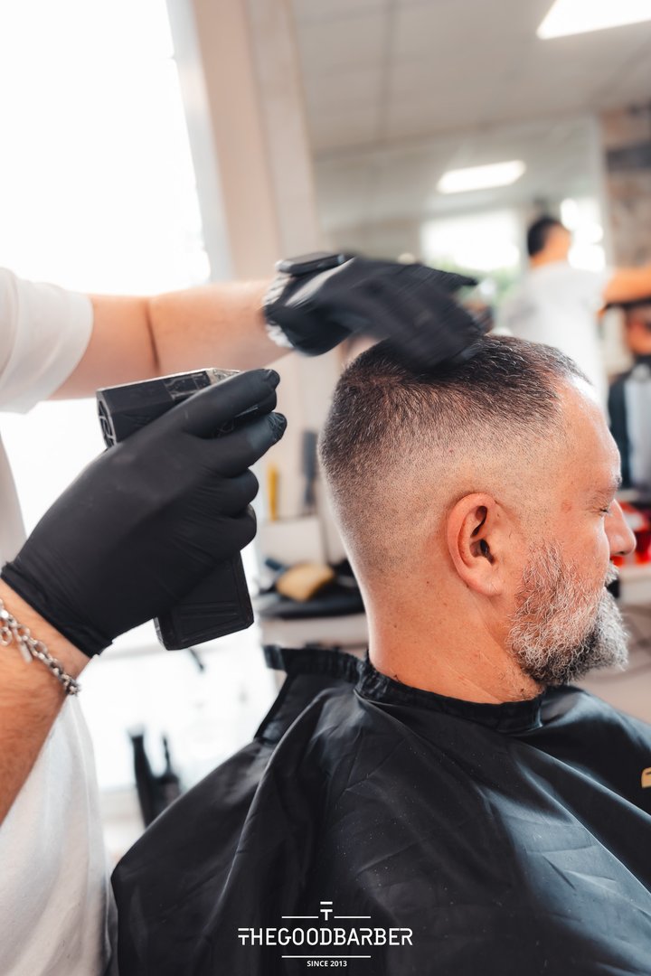 Corte fade con máquina eléctrica en perfil en The Good Barber
