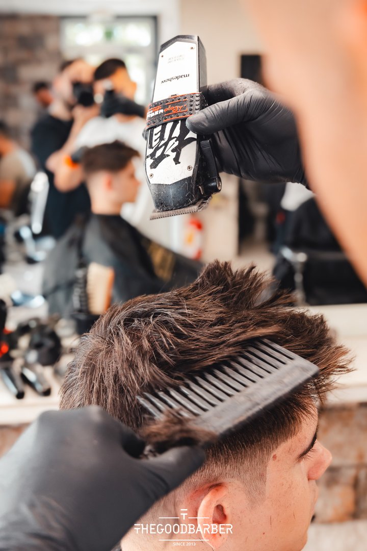 Barbero perfilando el cabello con peine y máquina en The Good Barber